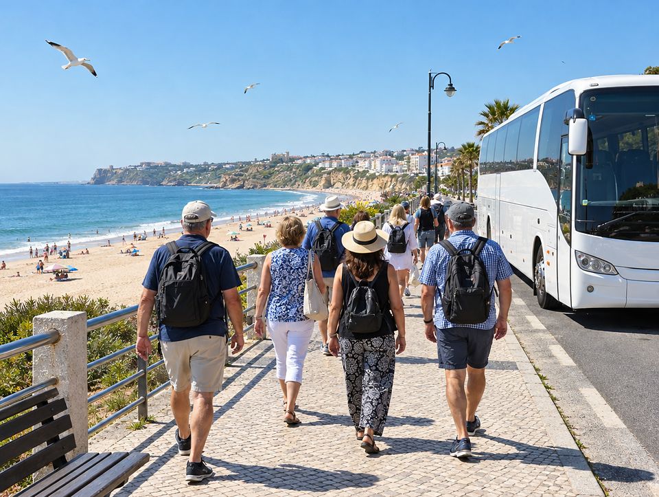Grupa turystów na nadmorskiej promenadzie, obok autokar i szeroka plaża